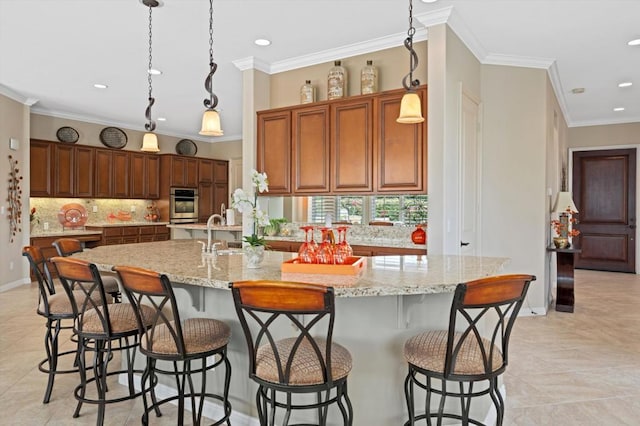 kitchen with crown molding, decorative light fixtures, light stone countertops, a large island, and a breakfast bar area