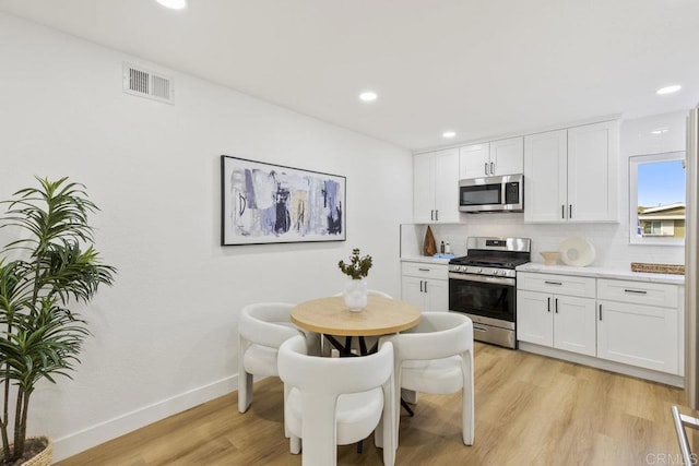 kitchen featuring stainless steel appliances, tasteful backsplash, white cabinets, and light hardwood / wood-style floors