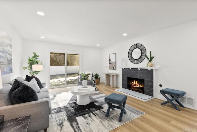 living room with a fireplace and light wood-type flooring