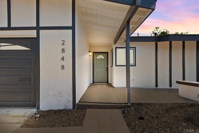 exterior entry at dusk featuring a garage