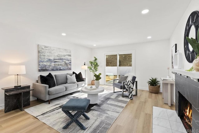 living room featuring a tiled fireplace and light hardwood / wood-style floors