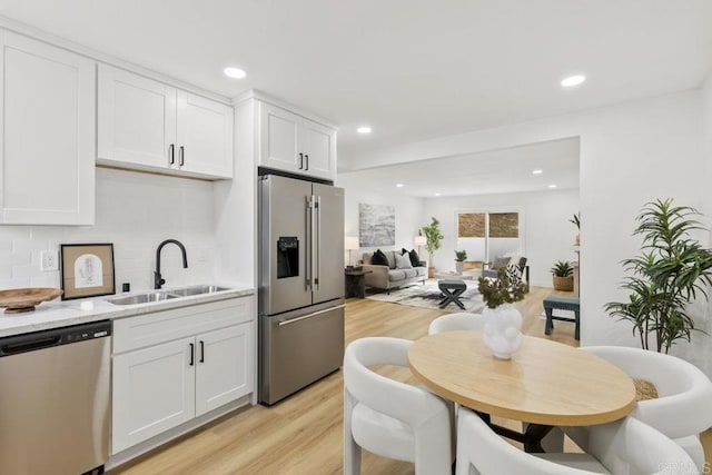 kitchen featuring stainless steel appliances, white cabinetry, sink, and backsplash