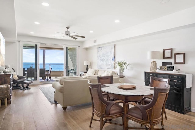 dining area featuring a water view, light wood-type flooring, and ceiling fan