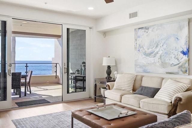 living room with a water view, ceiling fan, and light hardwood / wood-style floors