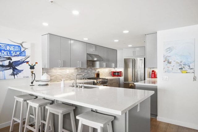 kitchen featuring a breakfast bar, kitchen peninsula, gray cabinets, and high end appliances