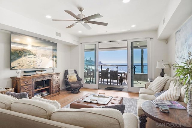 living room with ceiling fan, hardwood / wood-style floors, and a water view