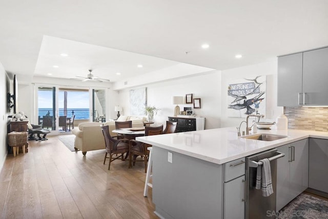 kitchen featuring dishwasher, kitchen peninsula, a water view, and gray cabinetry