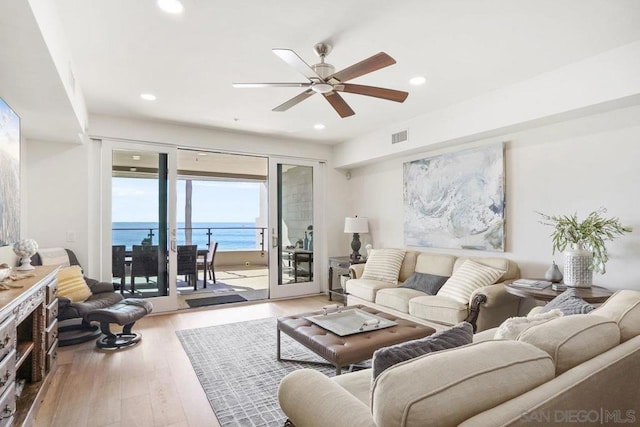 living room with a water view, ceiling fan, and light hardwood / wood-style floors