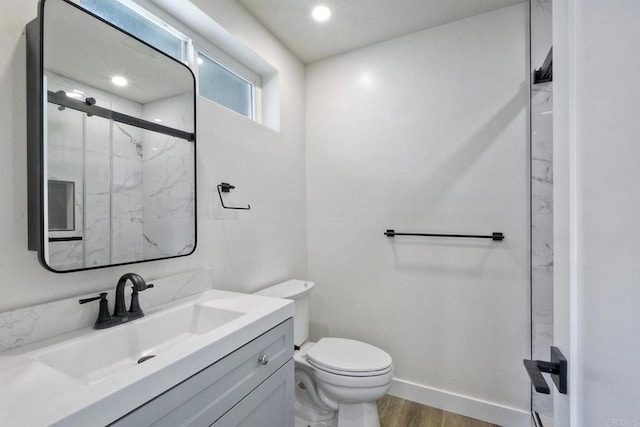 bathroom featuring vanity, a shower with shower door, wood-type flooring, and toilet