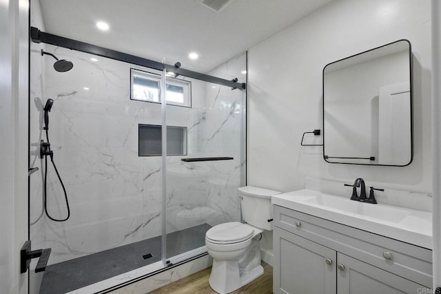 bathroom featuring toilet, a shower with shower door, hardwood / wood-style floors, and vanity