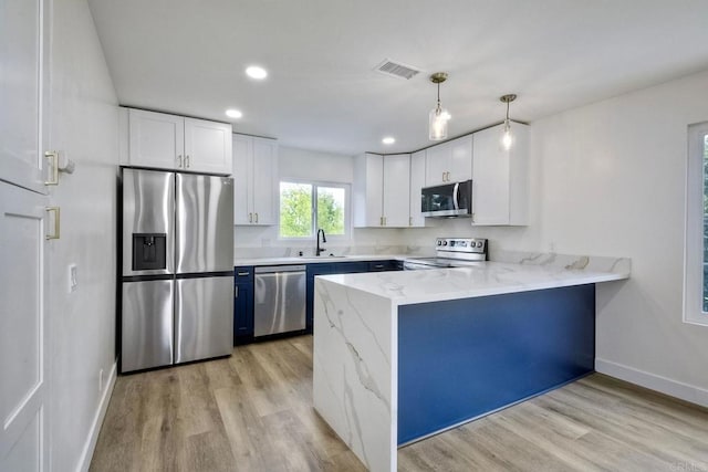 kitchen with kitchen peninsula, stainless steel appliances, sink, decorative light fixtures, and white cabinets