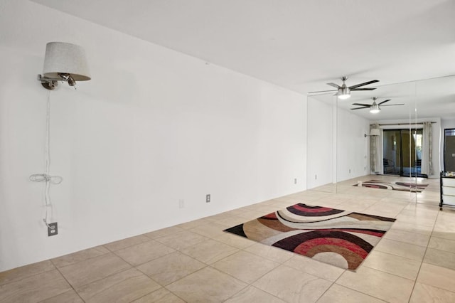 empty room with ceiling fan and light tile patterned flooring