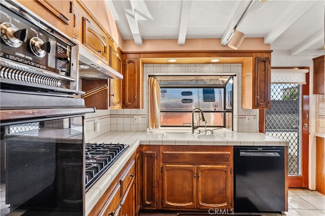 kitchen with black dishwasher, sink, beamed ceiling, tile counters, and decorative backsplash