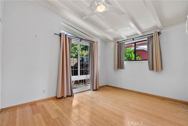 spare room with a wealth of natural light, lofted ceiling with beams, light hardwood / wood-style floors, and ceiling fan