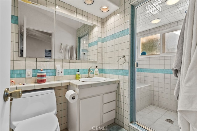 bathroom with toilet, an enclosed shower, vanity, and tile walls