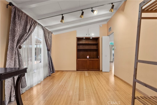 interior space with lofted ceiling with beams, rail lighting, and light wood-type flooring