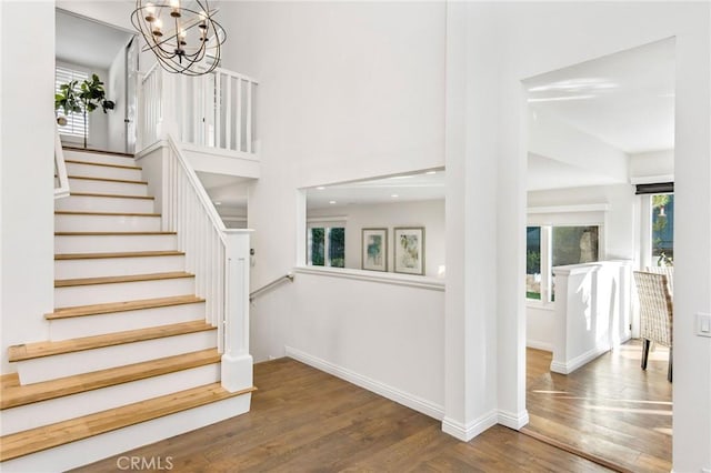 stairs with hardwood / wood-style floors and a chandelier