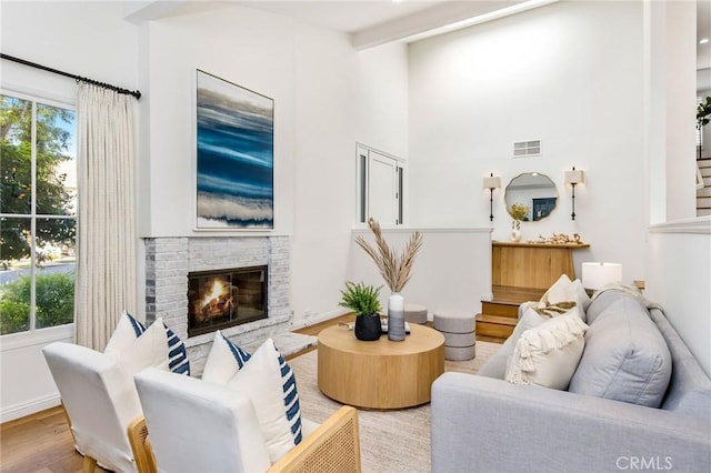 living room featuring light hardwood / wood-style floors, beam ceiling, and a fireplace