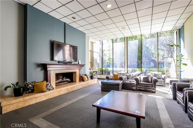 living room with expansive windows, carpet floors, a tile fireplace, and a paneled ceiling