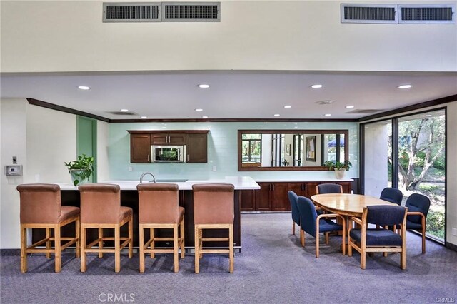 dining room with crown molding and dark colored carpet