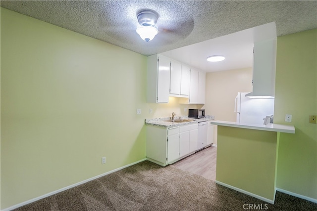 kitchen with kitchen peninsula, white cabinets, light colored carpet, and white appliances