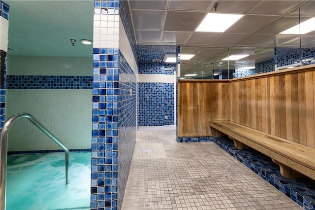 bathroom with wooden walls, a shower, tile walls, and tile patterned flooring