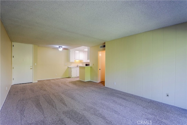 unfurnished living room with a textured ceiling and light colored carpet