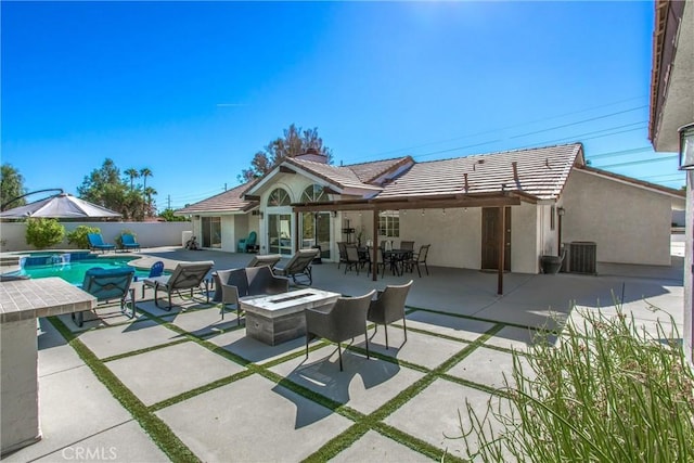 rear view of property with a patio area, a fenced in pool, an outdoor fire pit, and central AC