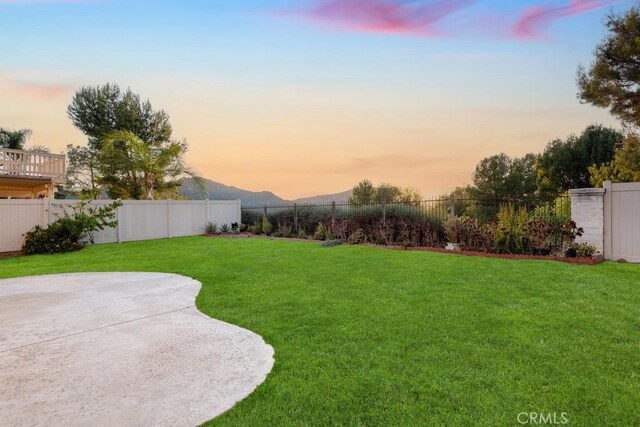 yard at dusk featuring a mountain view and a patio