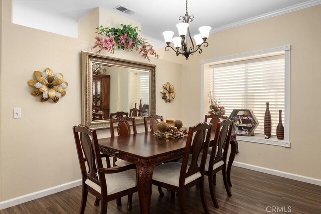 dining space with dark hardwood / wood-style floors, ornamental molding, and an inviting chandelier