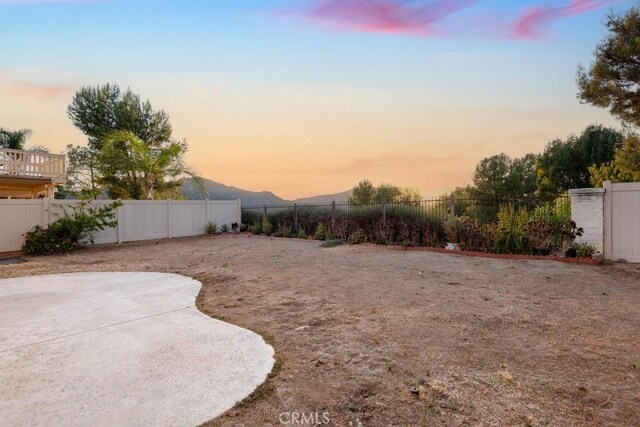 yard at dusk with a patio area and a mountain view