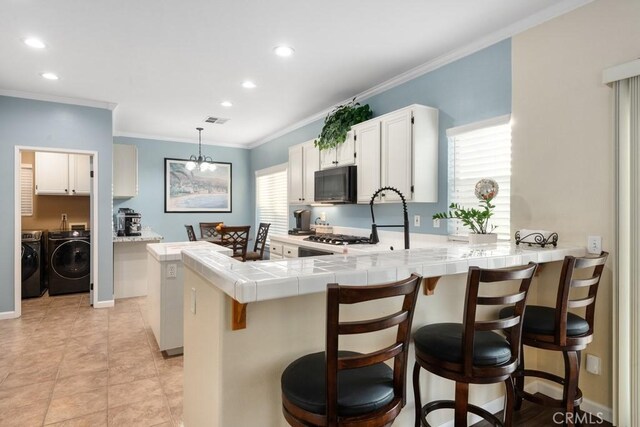 kitchen with kitchen peninsula, decorative light fixtures, white cabinets, and crown molding