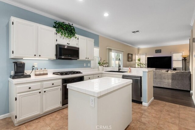 kitchen with white cabinetry, sink, a kitchen island, and appliances with stainless steel finishes