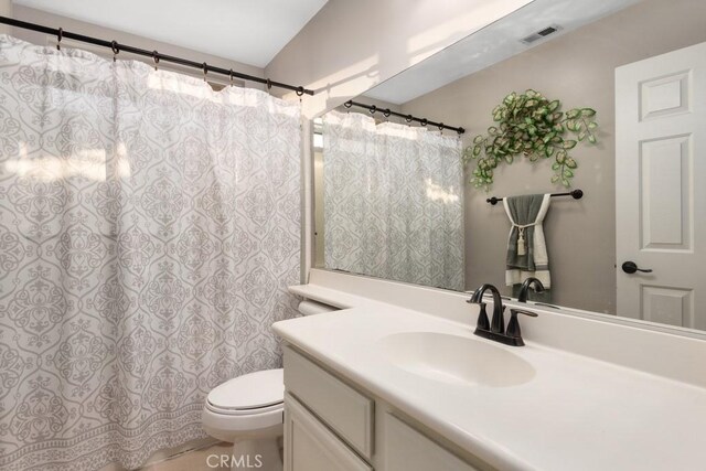 bathroom featuring vanity, toilet, and lofted ceiling