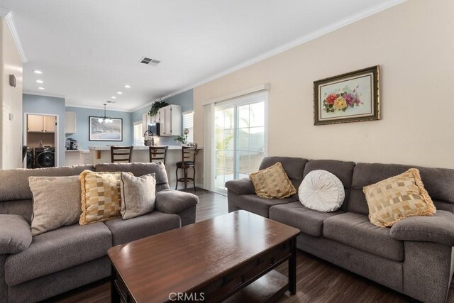 living room with washer and clothes dryer, dark wood-type flooring, and ornamental molding