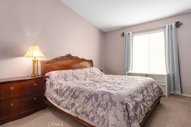 bedroom with light carpet and lofted ceiling