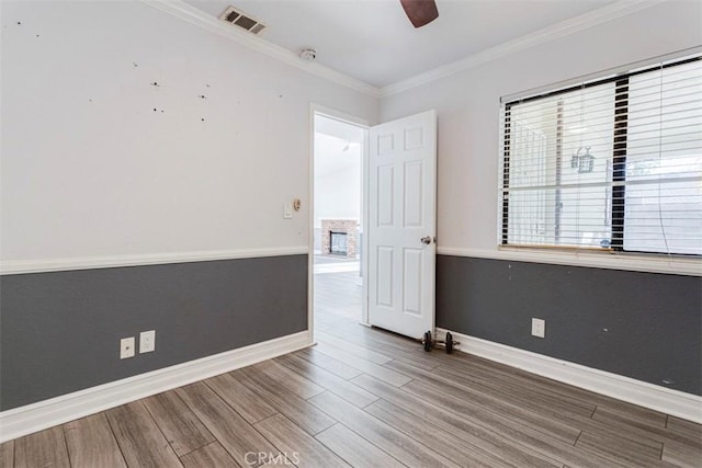 unfurnished room with a wealth of natural light, wood-type flooring, and ornamental molding