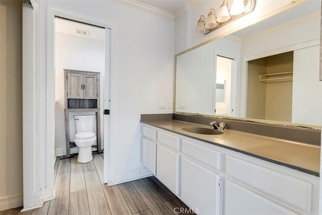 bathroom featuring vanity, hardwood / wood-style flooring, toilet, and ornamental molding