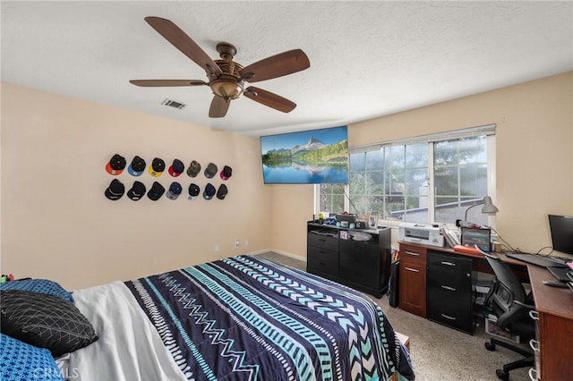 bedroom with ceiling fan, light carpet, and a textured ceiling