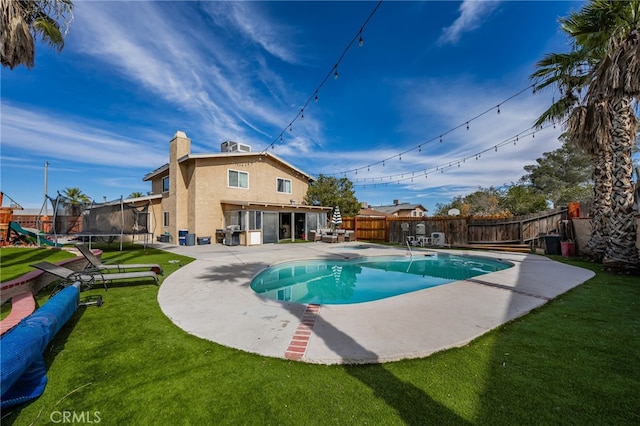 view of pool featuring a patio, a lawn, and a trampoline