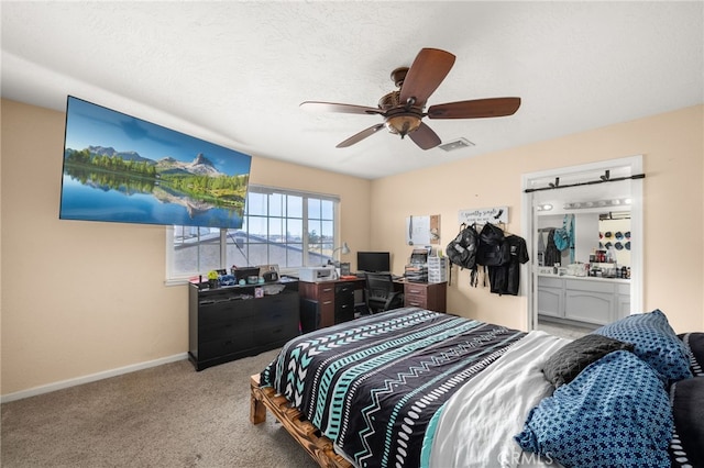 carpeted bedroom featuring a textured ceiling, ensuite bathroom, and ceiling fan