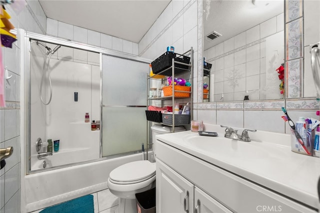 full bathroom with tile walls, shower / bath combination with glass door, toilet, vanity, and tile patterned flooring