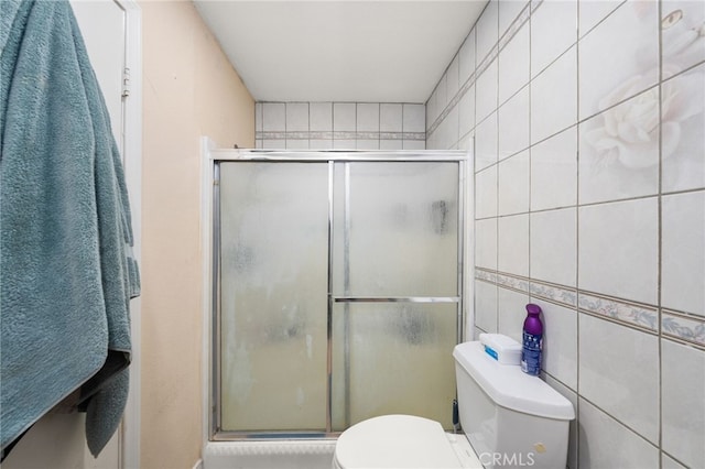 bathroom with toilet, tile walls, and a shower with shower door