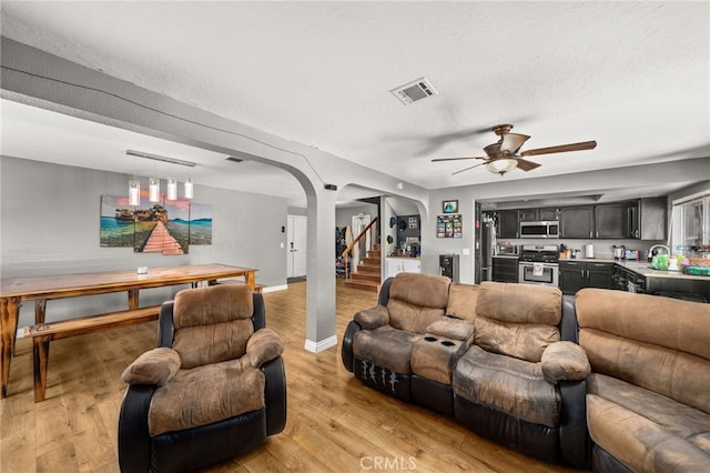 living room with ceiling fan, a textured ceiling, sink, and light wood-type flooring