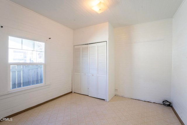 unfurnished bedroom with a closet and brick wall