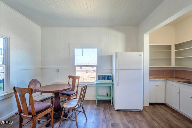 dining area featuring crown molding, hardwood / wood-style flooring, wooden walls, and sink