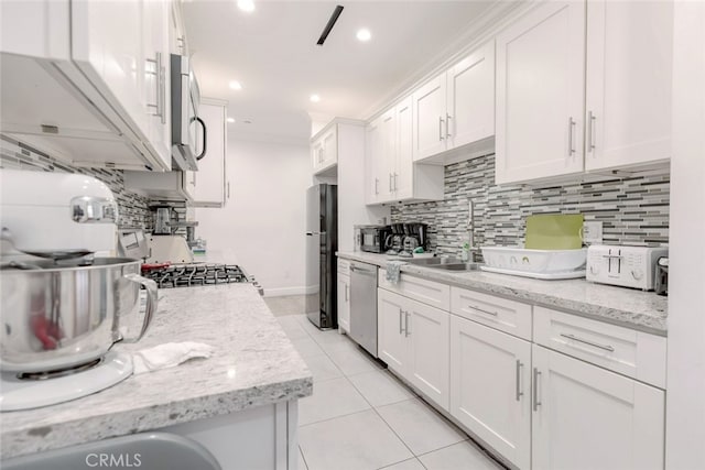 kitchen with light stone counters, white cabinets, light tile patterned floors, and appliances with stainless steel finishes