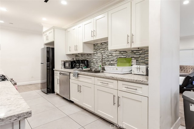 kitchen with decorative backsplash, white cabinets, ornamental molding, and appliances with stainless steel finishes