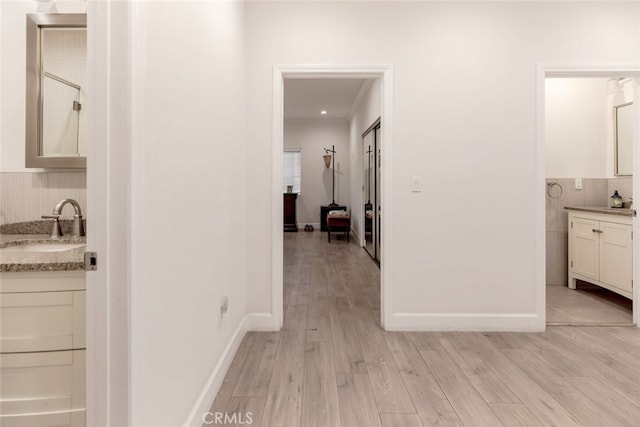 hall featuring sink, light hardwood / wood-style floors, and ornamental molding