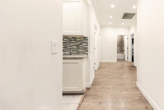 corridor with light hardwood / wood-style floors and ornamental molding